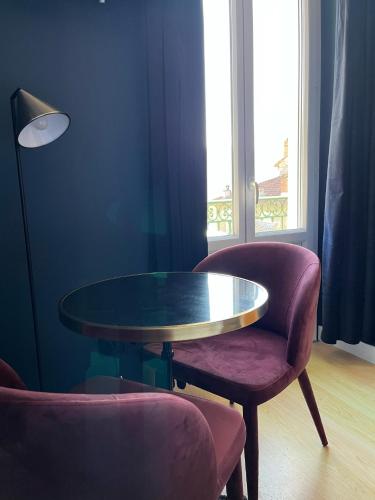 a table and chairs in a room with a window at Ostan Hôtel Boutique in Roquebillière
