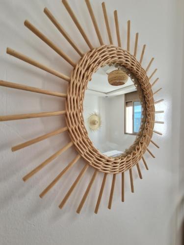 a rattan sunburst mirror hanging on a wall at cactus surf house in Tamraght Ouzdar