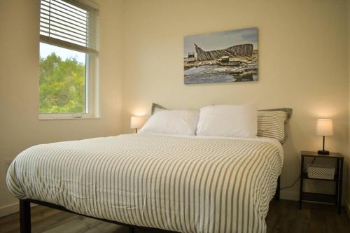 a bed in a bedroom with two lamps and a window at Rockfish Retreat at Kachemak Bay Kabins in Homer