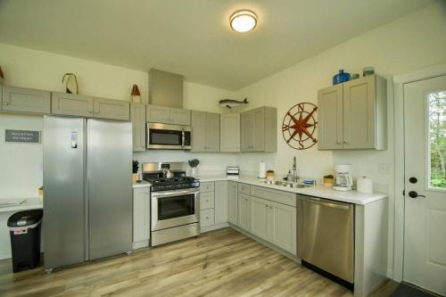 a kitchen with white cabinets and stainless steel appliances at Rockfish Retreat at Kachemak Bay Kabins in Homer