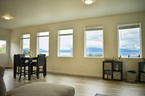 a living room with a table and chairs and windows at Rockfish Retreat at Kachemak Bay Kabins in Homer