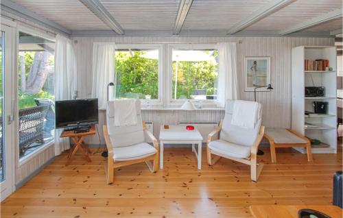 a living room with two white chairs and a television at Cozy Home In Samsø With Kitchen in Nordby