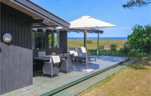 a wooden deck with a table and an umbrella at Cozy Home In Samsø With Kitchen in Nordby