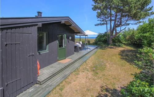 a black shed with a wooden deck next to a yard at Cozy Home In Samsø With Kitchen in Nordby