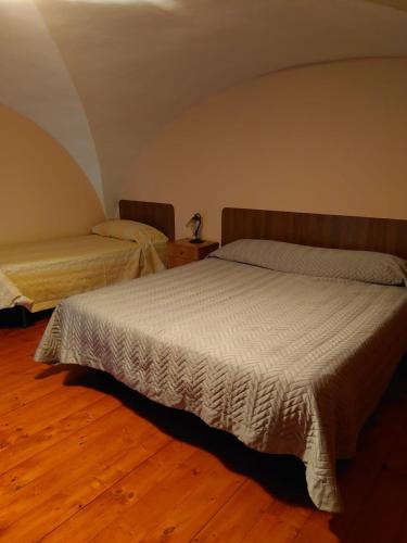 a bedroom with two beds and a wooden floor at CASEVACANZASOTTOLETNA in Giarre