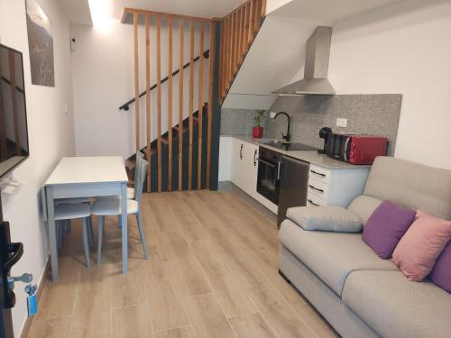a living room with a couch and a table and a kitchen at Armada Sacra A Teixeira in Ourense