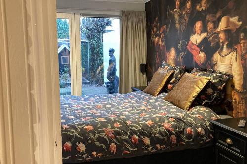 een slaapkamer met een bed met een groot schilderij aan de muur bij Voorsterstaete former barn, including jacuzzi in Voorst