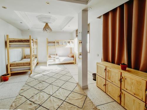 a room with several bunk beds and a room with a hallway at cactus surf house in Tamraght Ouzdar