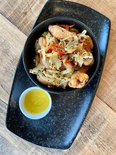 a black plate with a bowl of food and a sauce at Woodcote Hotel in Hooton