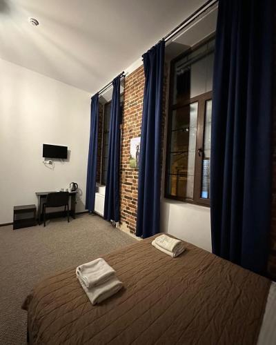 Un dormitorio con una cama con cortinas azules y un escritorio. en Hotel Rover, en Leópolis