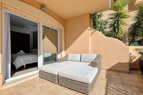 - un canapé en osier installé sur une terrasse avec une chambre dans l'établissement Stunning 2 Bedroom Apartment in Aloha Hill Club, à Marbella