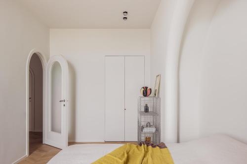 a bedroom with white walls and a bed with a yellow blanket at DUNE DU PALACE in Zeebrugge
