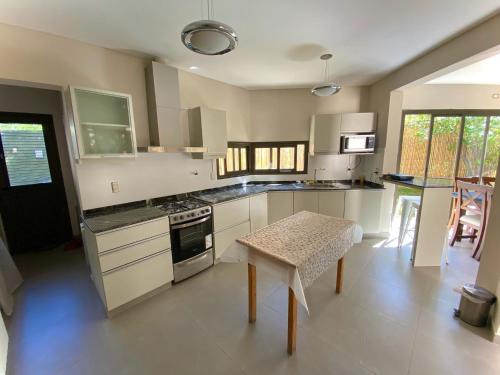 eine Küche mit weißen Schränken und einem Tisch darin in der Unterkunft ENCANTO DE CHACRAS- Moderna-A metros de la plaza in Chacras de Coria