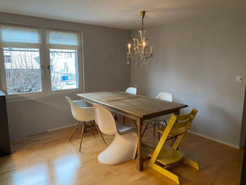 a dining room table with white chairs and a chandelier at Bijou in den Bergen in Disentis