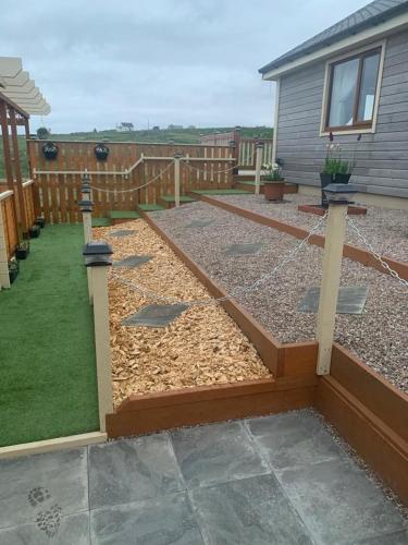 a backyard with a fence and a yard with a yard at Riverside Chalet Borve Isle of Lewis in Borve