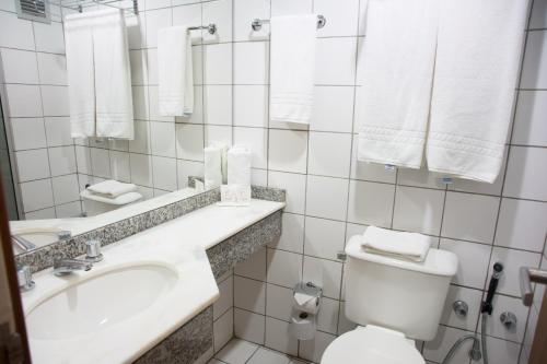 a bathroom with a toilet and a sink and towels at Hotel Continental Business - 200 metros do Complexo Hospitalar Santa Casa in Porto Alegre