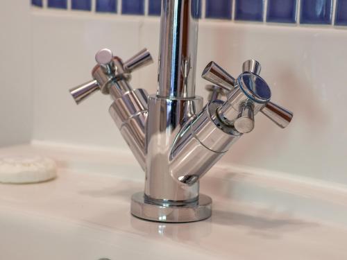 a chrome kitchen sink faucet on a counter at Hayloft Cottage in Staintondale