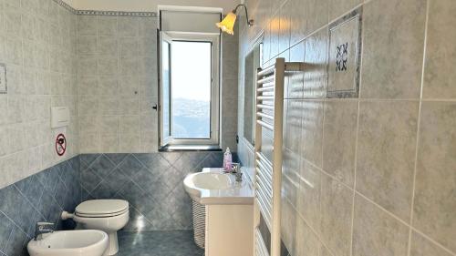 baño con aseo y lavabo y ventana en Dimora Alma camere panoramiche en Pianillo