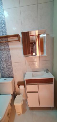 a bathroom with a sink and a toilet and a mirror at Apt 2 quartos, 5 pessoas em Container House in São Francisco do Sul