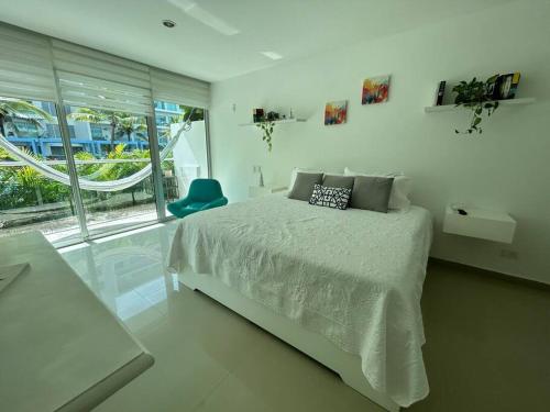 Un dormitorio blanco con una cama y una silla azul. en Beachfront Bliss-2BR Haven Steps from Sandy Shores, en Cartagena de Indias