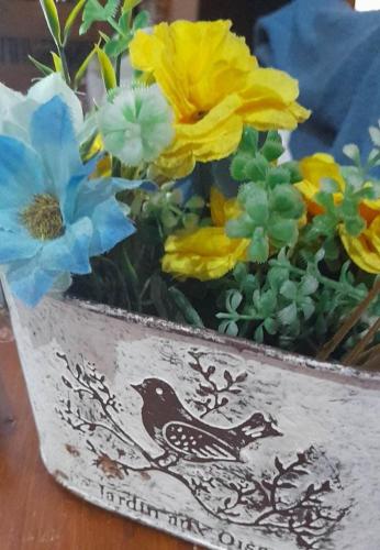 Un jarrón con flores amarillas y azules. en Casa en Estación Ramallo