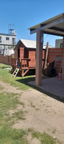 a wooden house with a porch and a building at Casa in Estación Ramallo