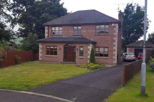 a brick house with a car parked in the driveway at Large private detached home in Dungiven
