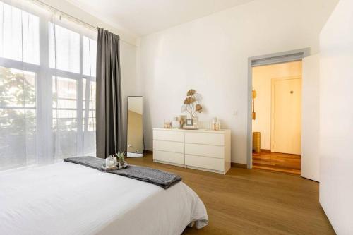 a white bedroom with a bed and a large window at Luxueux appart proche de gare du Midi, à côté du Centre Ville in Brussels