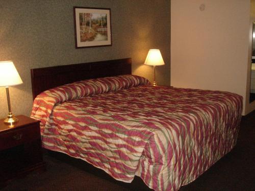 a hotel room with a bed and two lamps at German Village Inn Motel in Columbus