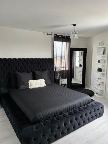 a large black bed in a room with a mirror at Appart duplex 87m2 près d’Airbus in Toulouse