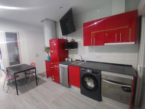 cocina con armarios rojos y lavadora en Espectacular apartamento con spa privado, en Miami Platja