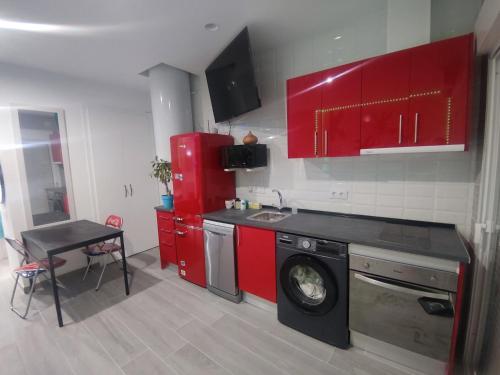 a kitchen with red cabinets and a washing machine at Espectacular apartamento con spa privado in Miami Platja