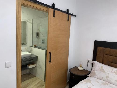 un baño con una puerta que conduce a un dormitorio con lavamanos en Casa rural Maila, en Malpartida de Cáceres