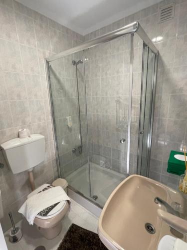 een badkamer met een douche, een toilet en een wastafel bij Casa Marques in Nazaré