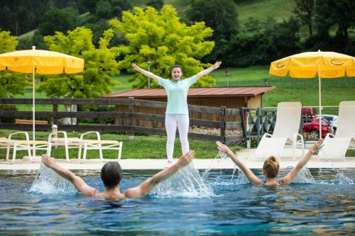 a woman standing on the edge of a swimming pool at Gesundheits- & Wellness Resort Weissenbach in Bad Weißenbach