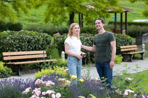 a man and woman standing in a garden with flowers at Gesundheits- & Wellness Resort Weissenbach in Bad Weißenbach