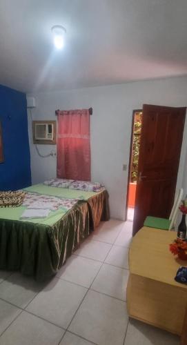 a bedroom with a bed and a window and a chair at Suites Solar dos Arcanjos Guaramiranga in Guaramiranga