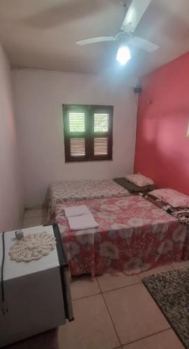 a bedroom with two beds and a red wall at Suites Solar dos Arcanjos Guaramiranga in Guaramiranga