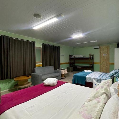 a hotel room with two beds and a couch at Entre serra pousada de altitudes in Urubici