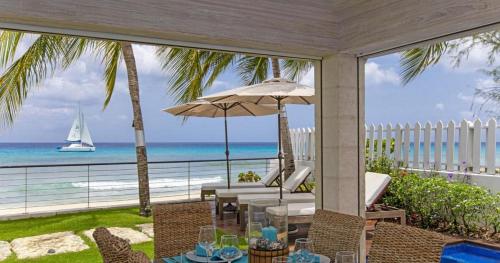 a patio with a view of the ocean and a sailboat at Radwood 2 by Barbados Sothebys International Realty in Saint James