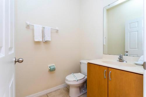 een badkamer met een toilet, een wastafel en een spiegel bij 3065 Beautiful comfortable home for your vacation in Kissimmee