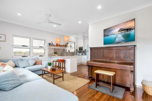 a living room with a couch and a piano at Kiki, 6 mins to Cairns and Airport, pet friendly in Cairns North