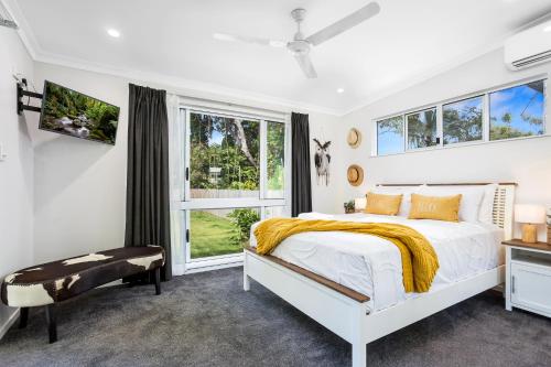 a white bedroom with a bed and a window at Kiki, 6 mins to Cairns and Airport, pet friendly in Cairns North