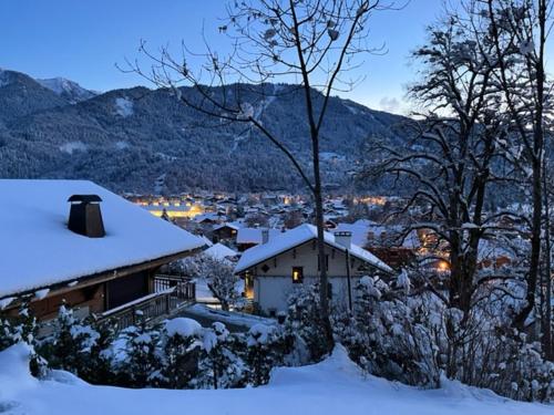 dom pokryty śniegiem z miastem w tle w obiekcie Pom Pom, 3 bedroom apt with stunning mountain views-Samoëns w mieście Samoëns