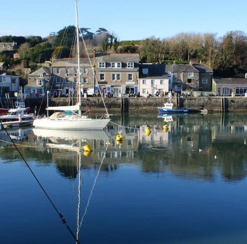 a boat is docked in a harbor with houses at Cosy Rustic Annex in quiet Cornwall Village in Saint Wenn