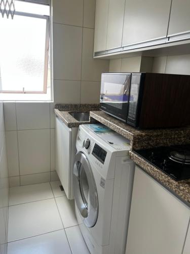 cocina con lavadora y microondas en Apartamento no centro de Curitiba,bem localizado e confortável, en Curitiba