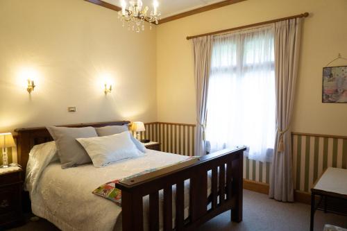 a bedroom with a bed with a chandelier and a window at Gumnut House. in Whanganui