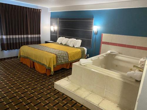 a hotel room with a bed and a bath tub at Faribault Hometown Inn & Suites in Faribault