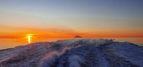 a boat in the ocean with the sunset in the background at Borgo di Santa Barbara in Santa Domenica