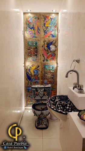a bathroom with a sink and a toilet and a mosaic wall at Hotel Temático Casa Puebla in Puebla